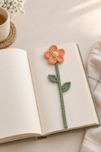 Finished apricot flower and sage-green crochet bookmark resting inside an open book