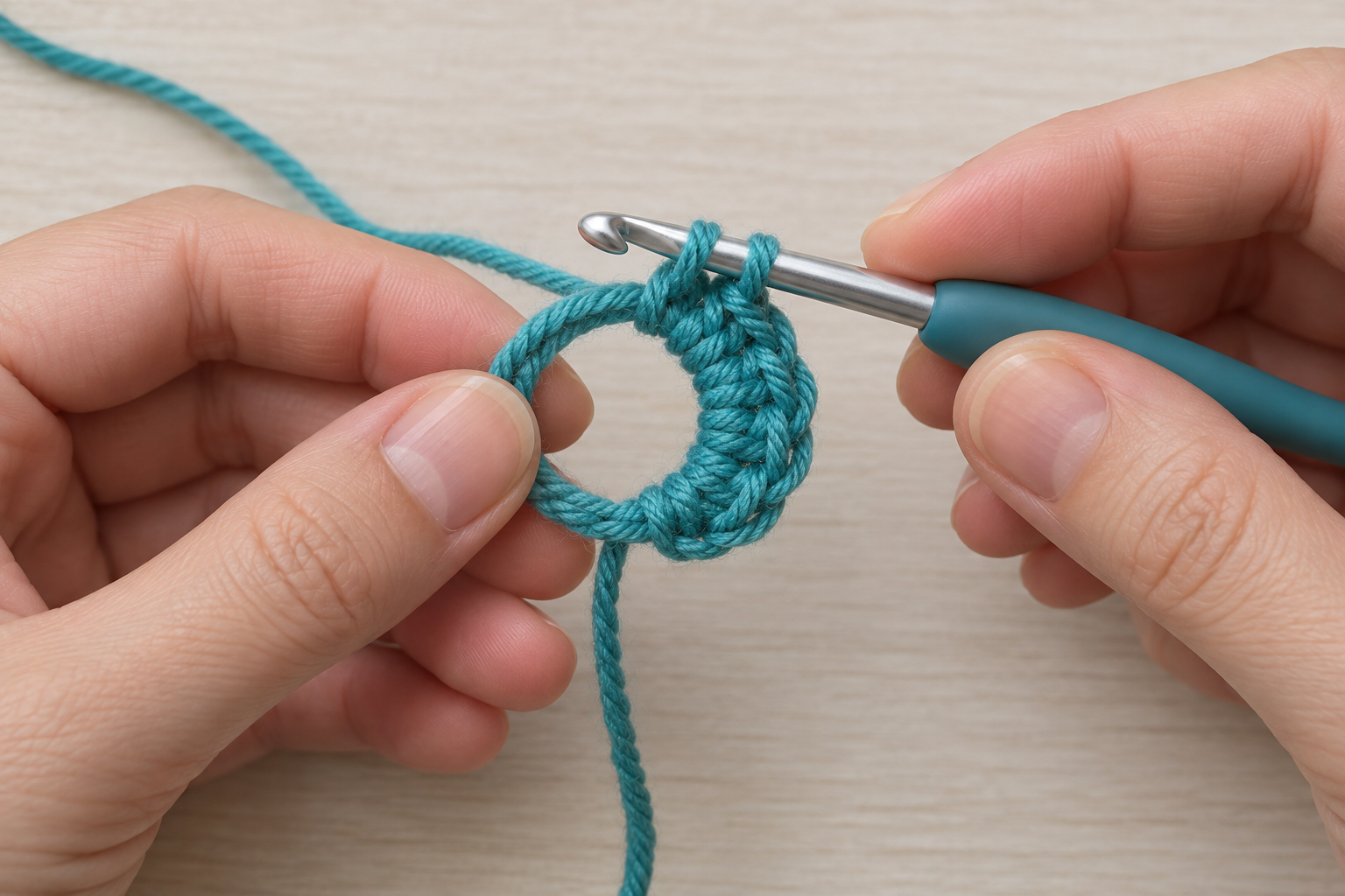 Hook making a teal single crochet into the large opening of a magic ring